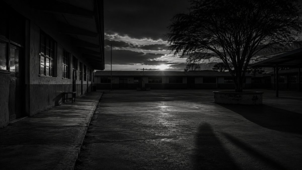 Un patio escolar vacío al atardecer con una sombra misteriosa