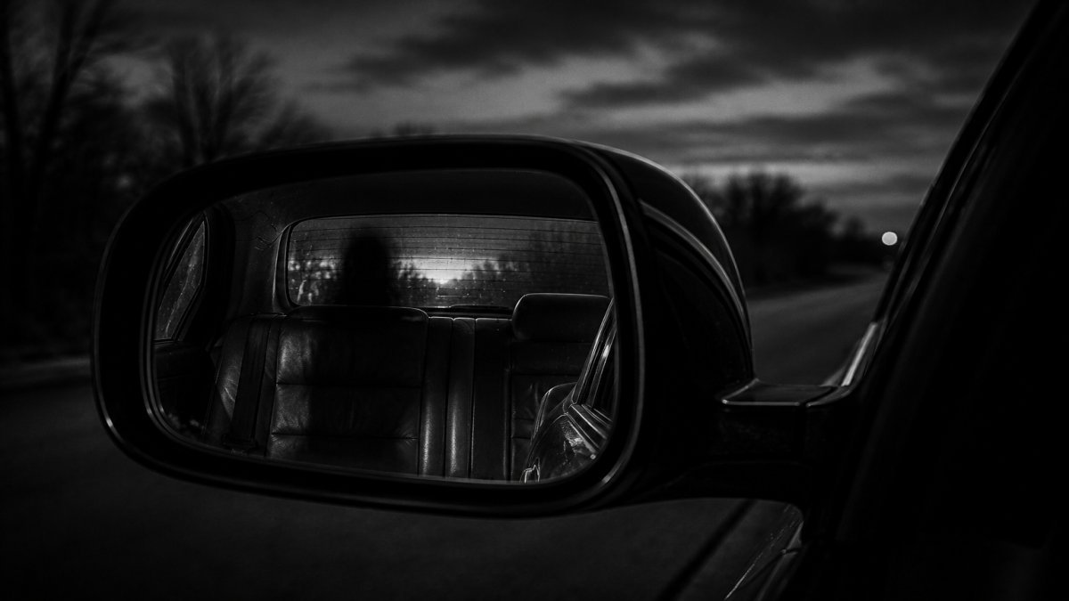 Retrovisor mostrando un asiento vacío pero con una sombra misteriosa
