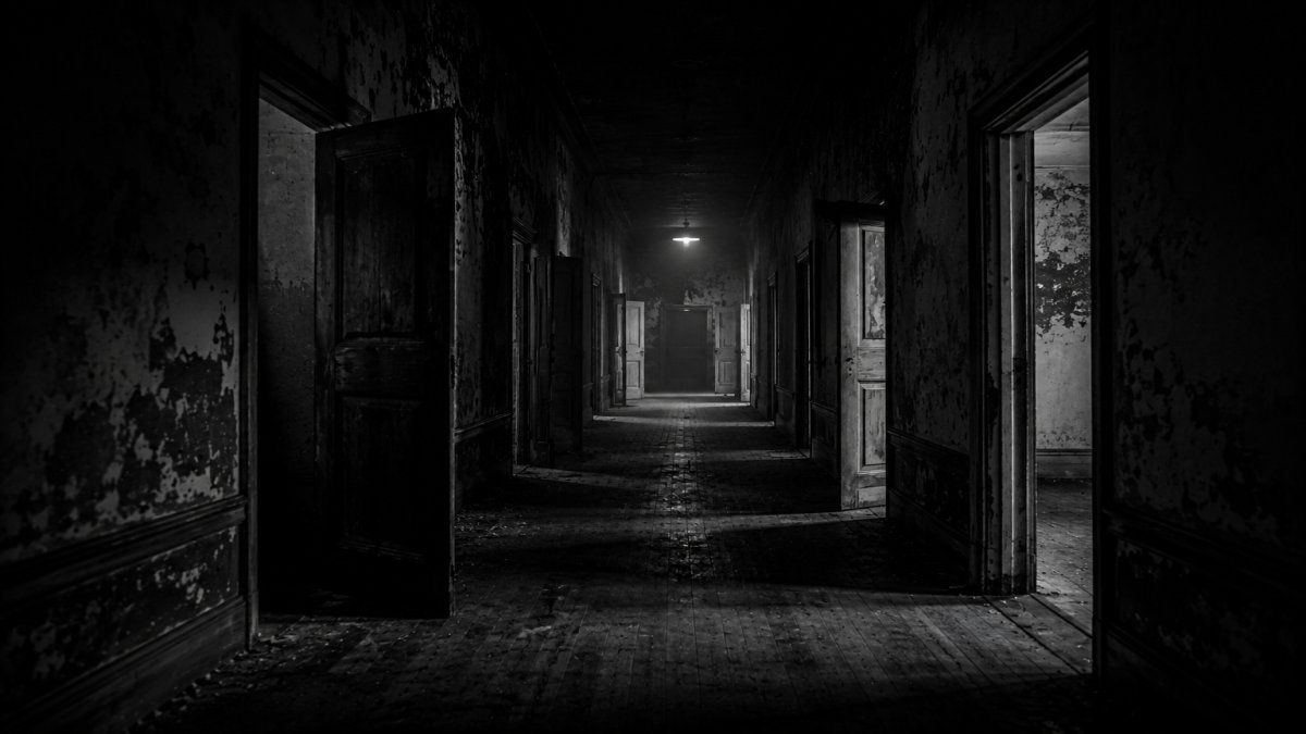 Un pasillo oscuro con puertas entreabiertas y sombras inquietantes